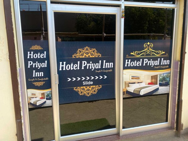 A hotel entrance with three glass doors, each displaying the hotel's name and a slide-out image of a room.