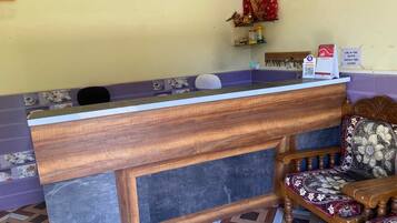 A reception desk with a wooden counter and a chair with a patterned cushion.