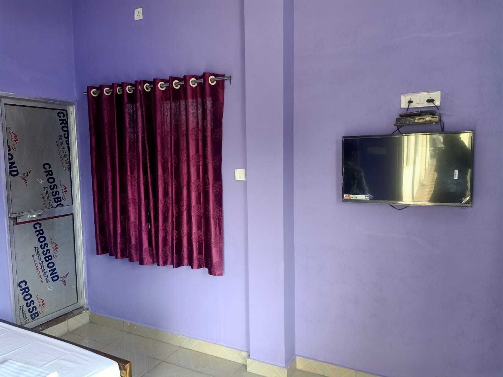 A bathroom with purple walls, a window with a metal frame, and a wall-mounted electrical outlet.