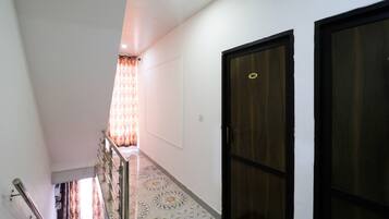 A corridor with a patterned floor, a staircase, and a door with a number plate.