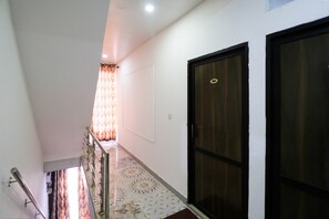 Un pasillo con piso estampado, una escalera y una puerta con placa de número.