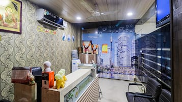 A reception area with patterned wallpaper, a reception desk, a water dispenser, and a cityscape mural on the wall.