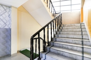 Una escalera con barandilla negra y peldaños de mármol.