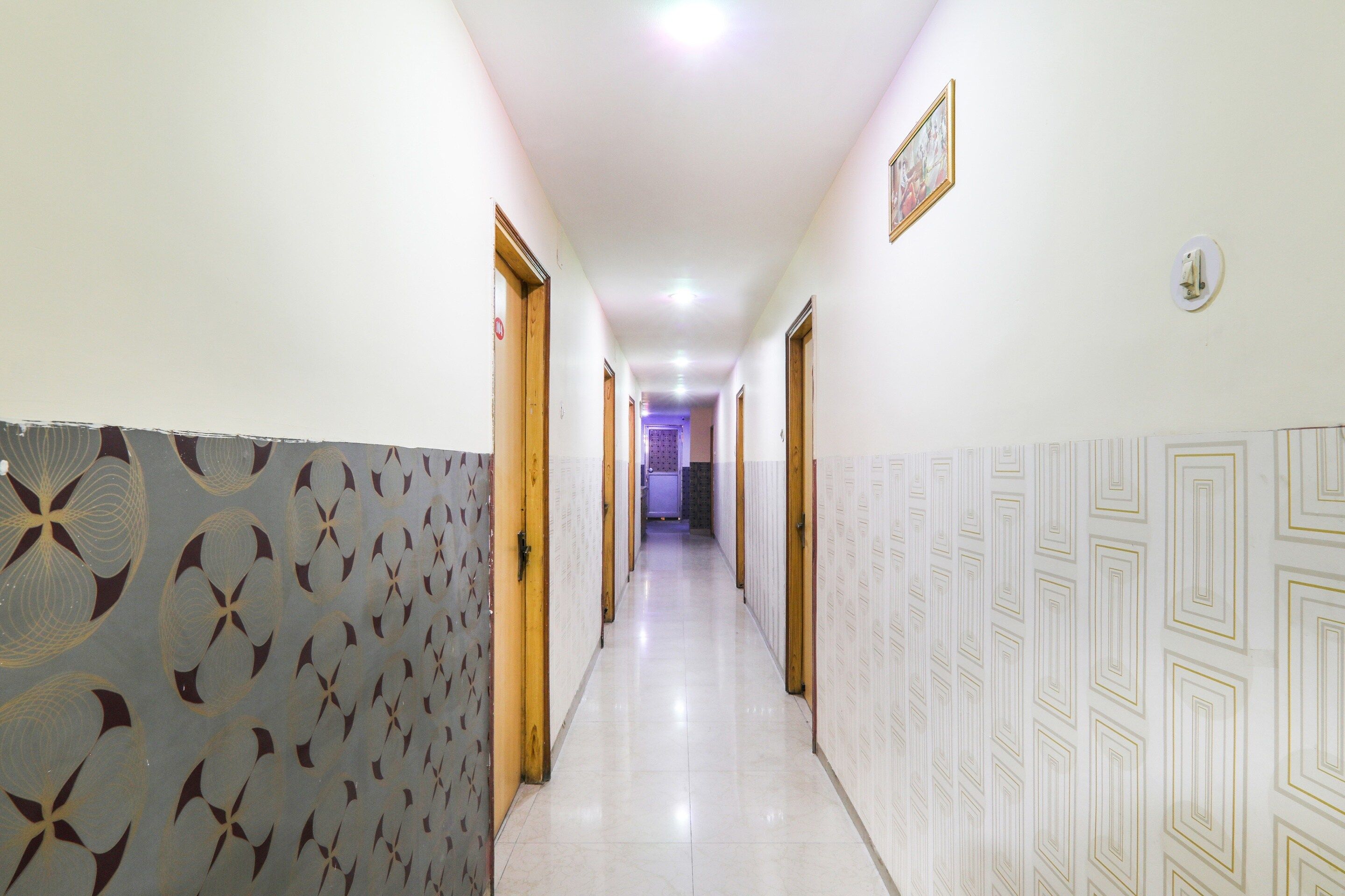 A hallway with patterned walls, doors, and a tiled floor.