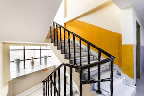 Una escalera con barandales negros y una pared amarilla destacada.