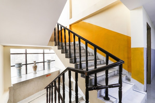 Una escalera con barandales negros y una pared amarilla destacada.