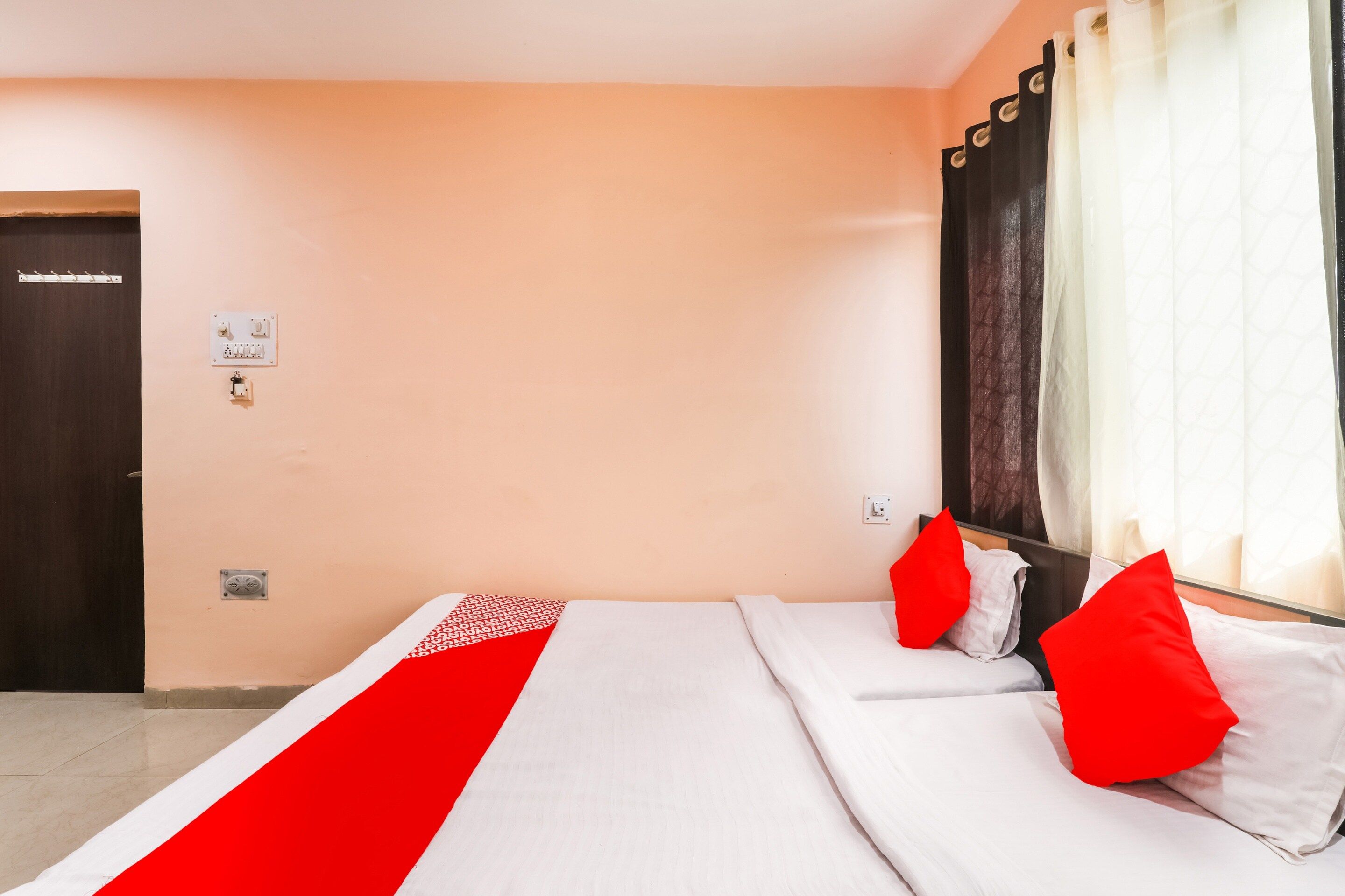 Una habitación de hotel con cama, puerta y ventana con cortinas.