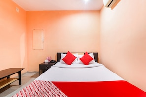 Una habitación de hotel con cama, mesita de noche y escritorio.