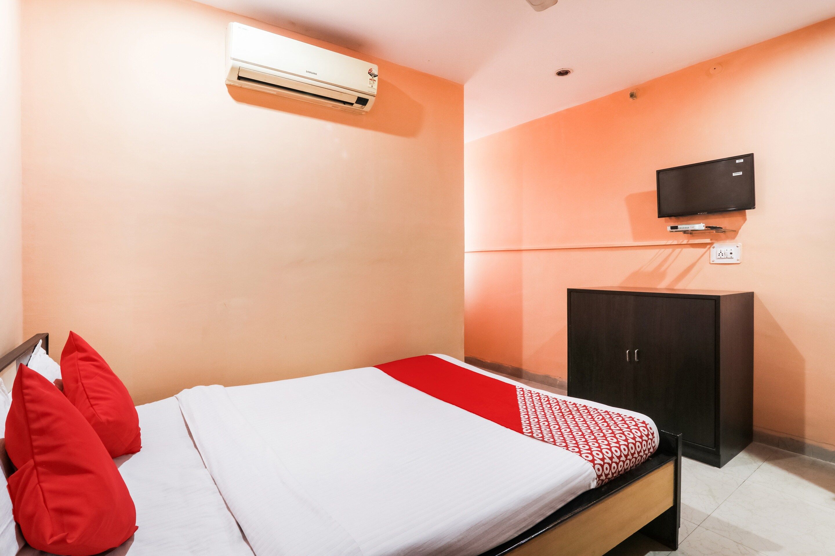 Een hotelkamer met een bed, een aan de muur bevestigde televisie en een kledingkast.