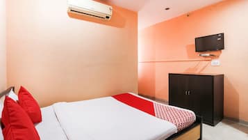 Een hotelkamer met een bed, een aan de muur bevestigde televisie en een kledingkast.