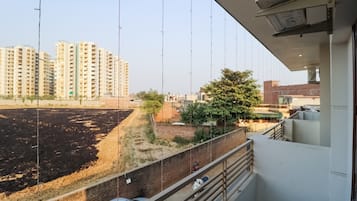 A balcony with a view of a construction site, a brick wall, and a tree.