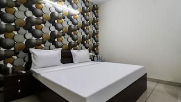 A modern bedroom with a large bed, a nightstand, and a wall with a textured pattern.