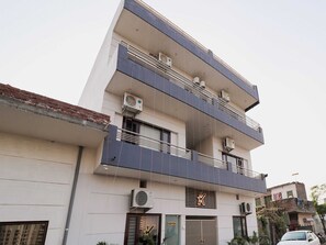 Un edificio de varios pisos con balcones, unidades de aire acondicionado y una recepción.