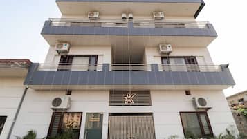 Un edificio de varios pisos con unidades de aire acondicionado, un cartel de recepción y una entrada con portón.