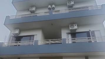 A multi-story building with balconies, air conditioning units, and windows.