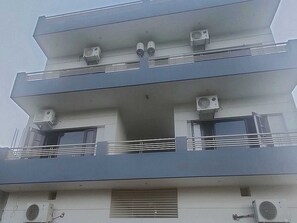 Un edificio de varios pisos con balcones, unidades de aire acondicionado y ventanas.