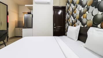 Una habitación de hotel con cama, escritorio, refrigerador y una pared decorada con motivos.