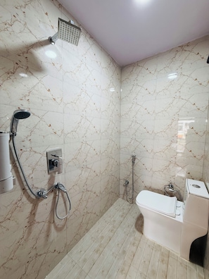A bathroom with a shower, toilet, and a hand shower. - Angan E Kashi (Varanasi)