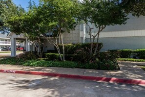 A building with a covered parking area, surrounded by trees and shrubs. - 1 Queen Bed|Non-smoking (Dallas)