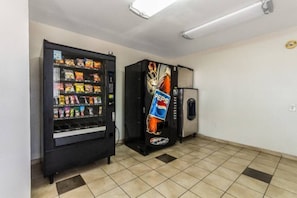A vending machine with snacks and a Pepsi refrigerator in a room with tiled flooring. - 1 Queen Bed|Non-smoking (Dallas)