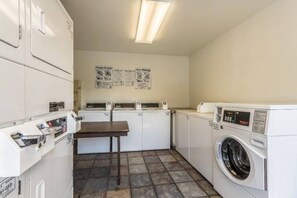 A laundry room with multiple washing machines, a drying rack, and a table. - 2 Full Beds | Smoking (Dallas)