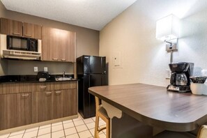 A compact kitchen with wooden cabinets, a black refrigerator, a microwave, and a coffee maker. - 2 Full Beds | Smoking (Dallas)