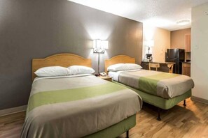 A hotel room with two beds, a desk, a chair, a lamp, and a kitchenette. - 2 Full Beds | Smoking (Dallas)