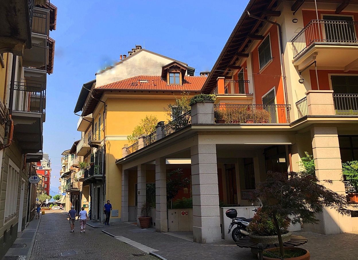 Una calle con edificios, cielo despejado y algunos peatones.