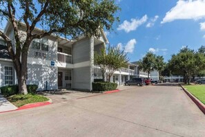 A multi-story motel with a parking lot and a clear sky. - 2 Full Beds | Non-Smoking (Dallas)
