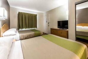 A hotel room with two beds, a television on a wooden dresser, and a door leading to another room. - 2 Full Beds | Non-Smoking (Dallas)
