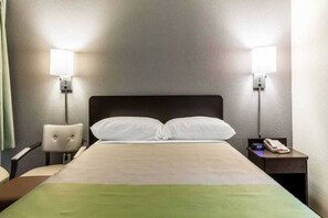 A hotel room with a bed, two bedside lamps, a chair, and a nightstand with a phone. - 1 Queen Bed | ADA/RI Shower| NS (Dallas)