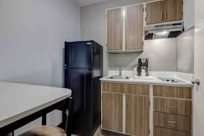 A compact kitchen with a refrigerator, sink, and wooden cabinets. - 2 Full Beds | ADA/Roll-In Shower, Smoking (Arlington)