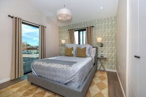 A modern bedroom with a large bed, two bedside lamps, a view through the window, and a patterned wall. - Wine Country Retreat • Walk To Downtown + Tasting Rooms | The Agave Room (Paso Robles)