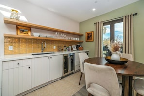 A modern kitchen with a built-in oven, a dining table with chairs, and a window with curtains. - Wine Country Retreat • Walk To Downtown + Tasting Rooms | The Agave Room (Paso Robles)