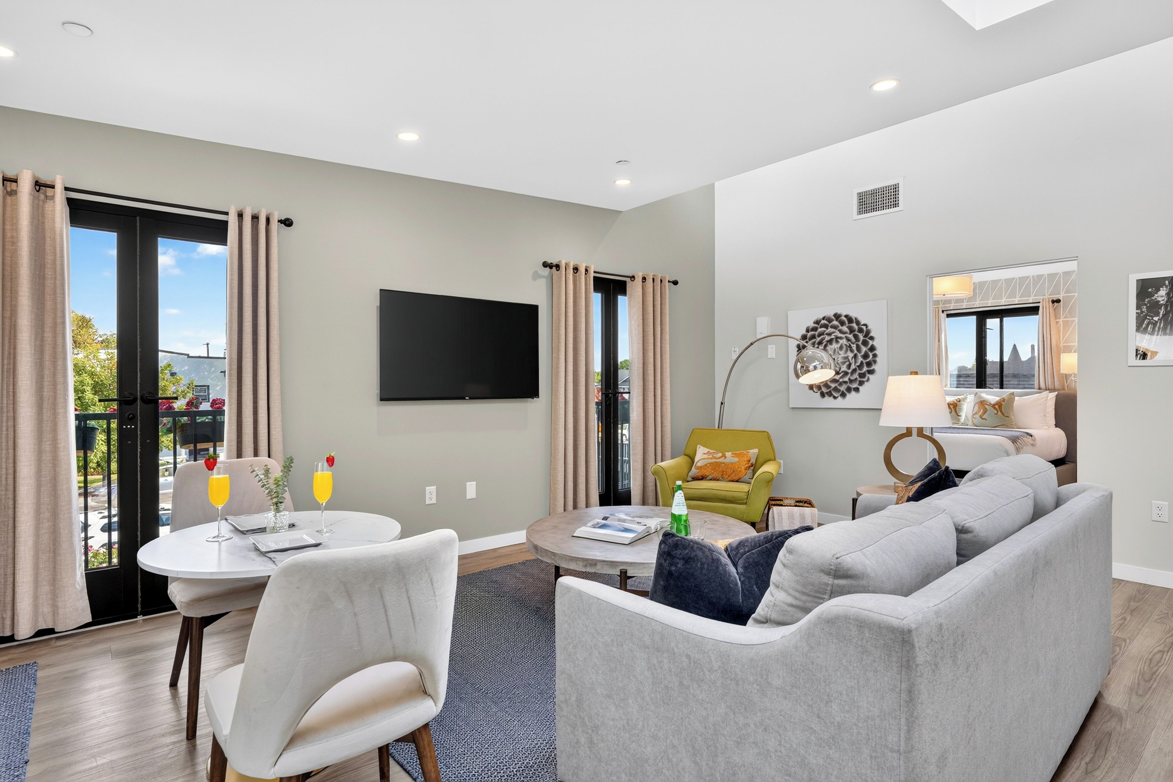 A modern living room with a grey sofa, a round coffee table, and a flat-screen TV mounted on the wall.