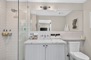 A modern bathroom with a glass shower enclosure, a vanity with a mirror, and a toilet. - Wine Country Retreat • Walk To Downtown + Tasting Rooms | The Agave Room (Paso Robles)