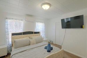 A bedroom with a bed, a television mounted on the wall, and a window with curtains. - Lovely Merrimack Valley Home Near Local Eats (Lawrence)