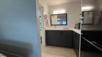 A modern kitchen with a dark countertop, a sink, and a microwave.