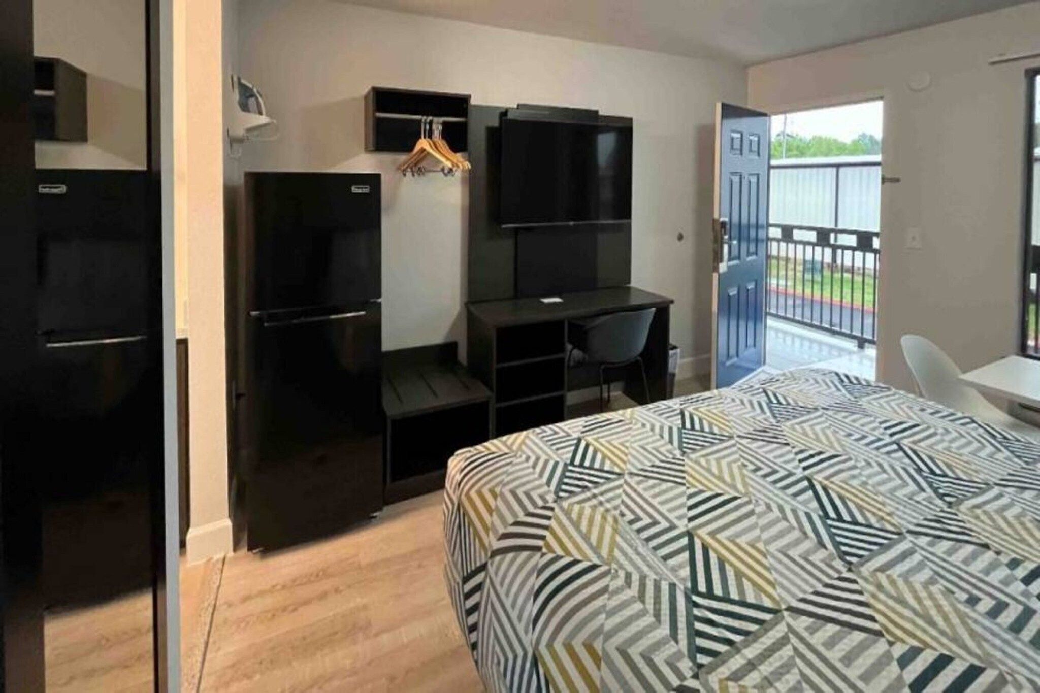 Una habitación de hotel pequeña con cama, escritorio, silla, armario y televisor.