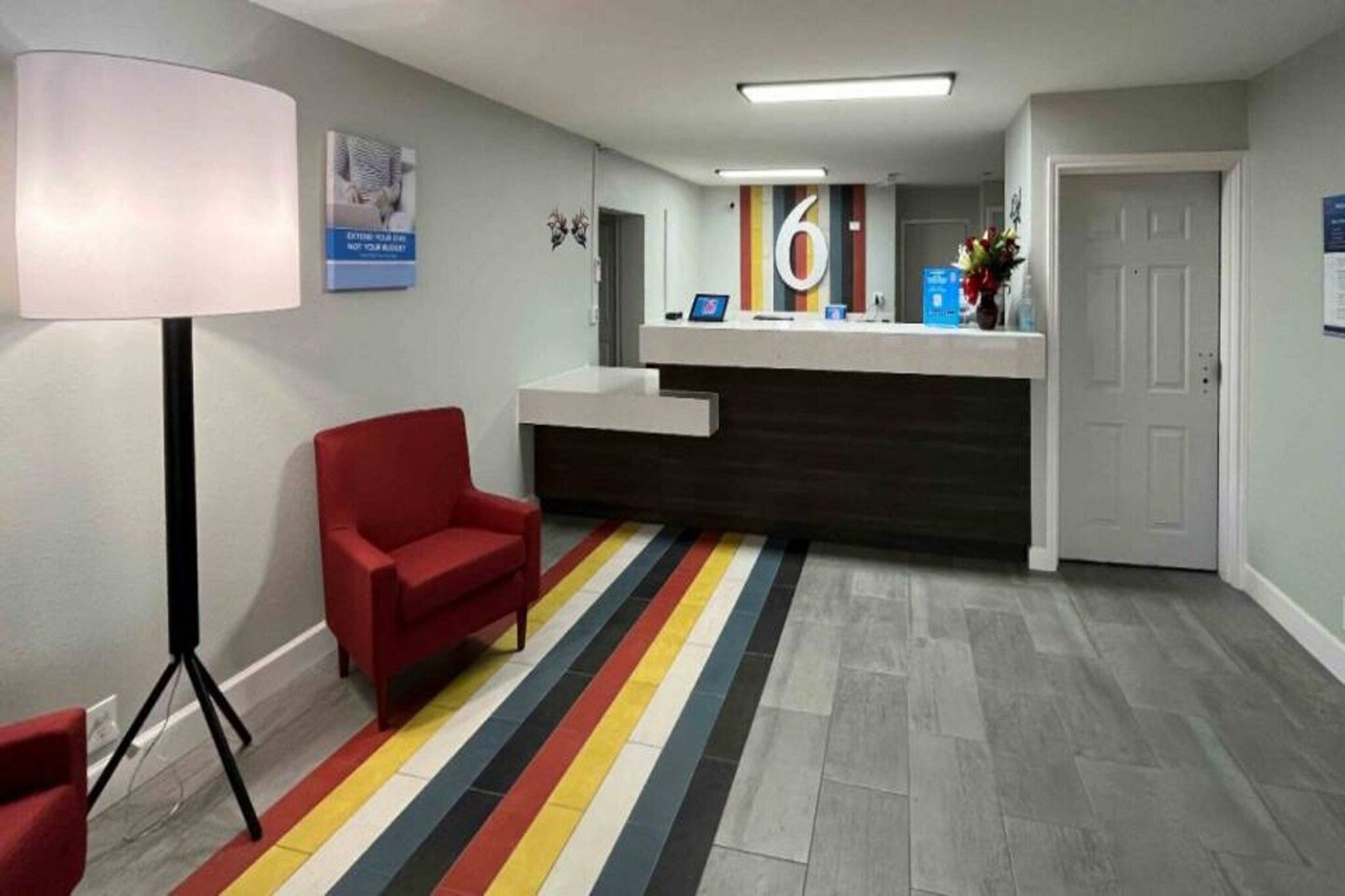 A reception area with a red chair, a desk, and a striped floor.