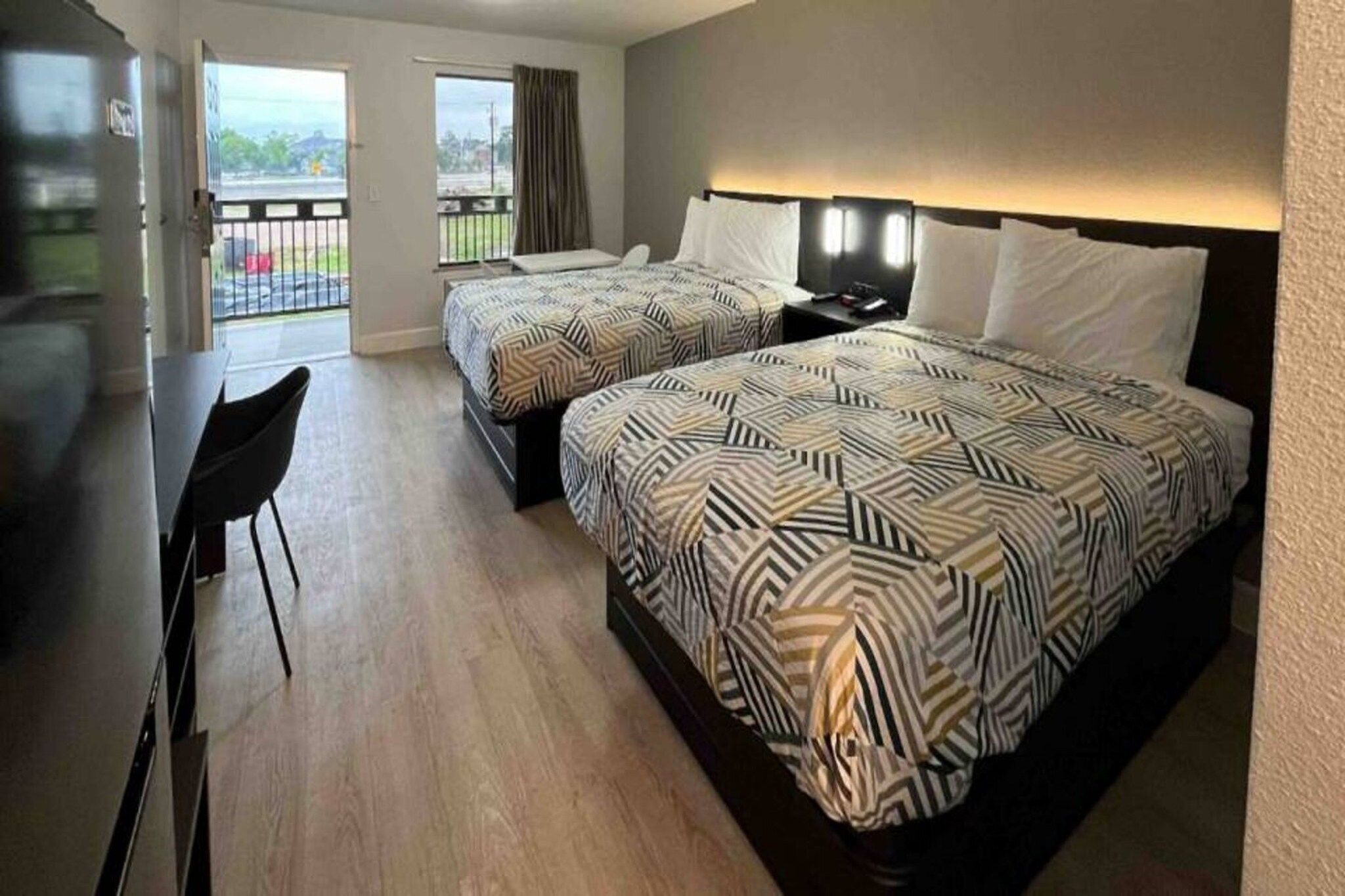 A hotel room with two beds, a desk, and a chair.