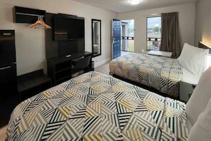 A hotel room with two beds, a desk, a television, and a balcony. - 2 Full Beds|Smoking| Kitchen (Conroe)