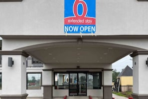 L'entrada d'un hotel per a estades llargues amb un cartell blau que indica que ja està obert.