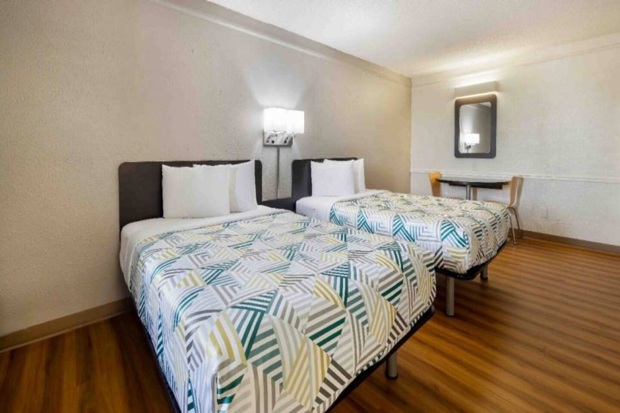 Une chambre d’hôtel avec deux lits, un petit bureau et une chaise.