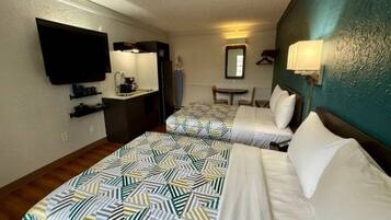 A hotel room with two beds, a desk, a television, and a mirror.