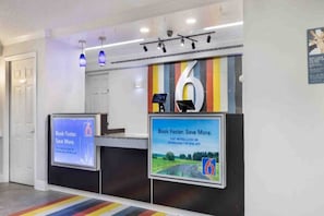 A reception desk with digital screens displaying promotional content. - 2 Full Beds|NS| Kitchen (Beaumont)