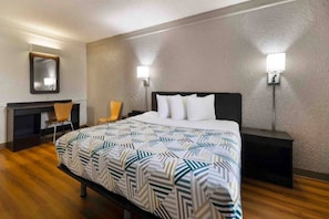 Ett hotellrum med en säng, två sängbord, en stol, ett skrivbord och en spegel på väggen.