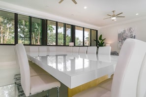 A modern meeting room with a long white table, white chairs, large windows, and a ceiling fan. - 8,000 sq ft Estate with Heated Pool & Game Room (Plantation)