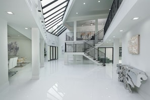 A spacious, modern interior with a central staircase, high ceilings, and a polished floor. - 8,000 sq ft Estate with Heated Pool & Game Room (Plantation)