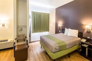 Een hotelkamer met een bed, nachtkastjes, een spiegel, een raam met gordijnen en een wandlamp.